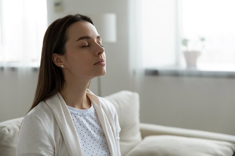 A woman relaxing on her couch breathing in fresh clean air