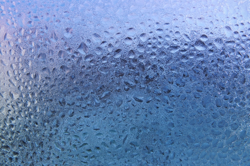 Water drops and frost on window glass, close-up natural texture. Controlling Humidity In Your Home.