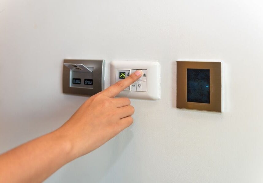 Image of someone pressing control panel attached to HVAC unit. Heat Pump Versus Furnace.