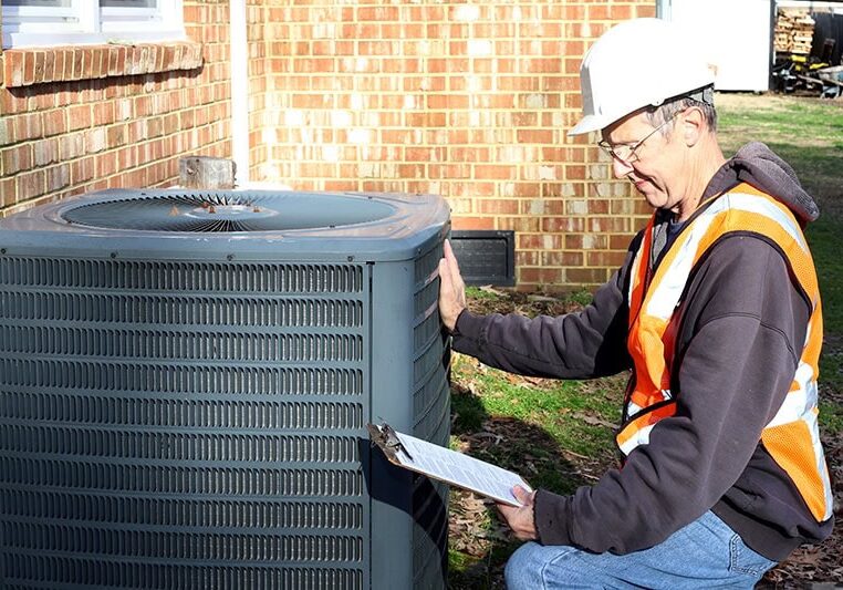 Home inspection of central air unit by a maintenance worker.