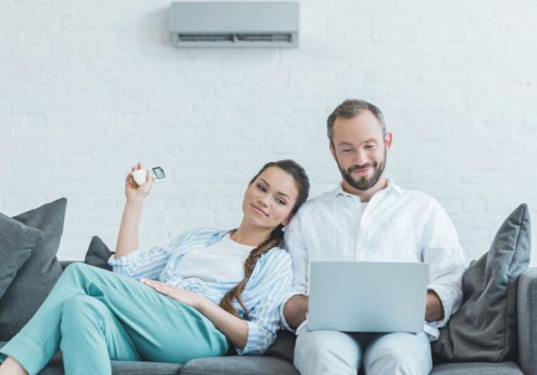 a man and woman sitting on a couch with a laptop.
