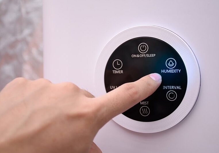 Close up man hand pressing the digital humidifier button on a smart humidifier in a smart home or green house.