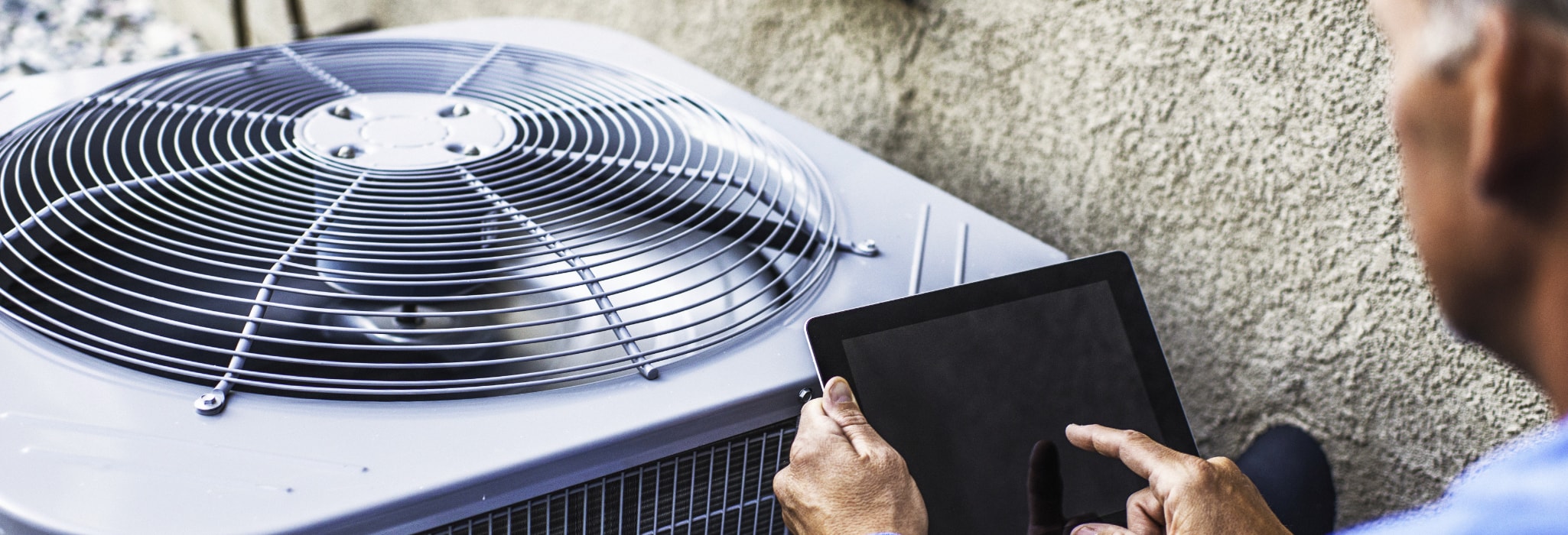 Maintenance engineer using digital tablet to inspect air conditioning unit.